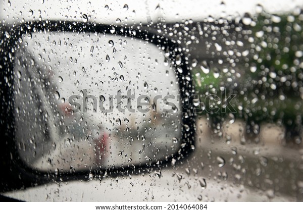 View of a car side mirror from inside
the car with condensation and rain on the glass
window