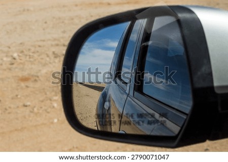 View in the car sidemirror in the barren empty landscape between Aus and Luderitz in Southern Namibia.