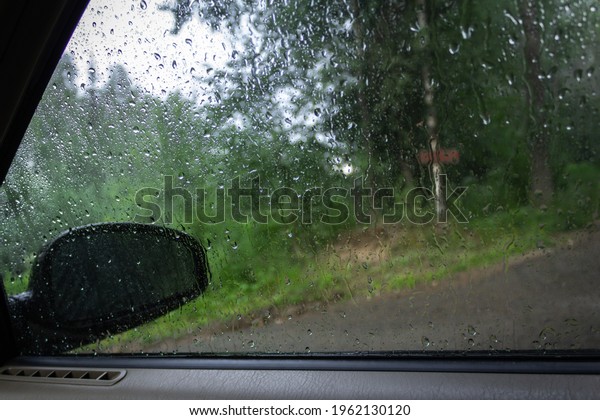 View from the car window in the rain through glass\
with water drops