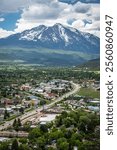 View of Carbondale, Colorado, showcasing lush valleys, a busy highway, and towering Mt Sopris under a cloudy sky during daylight hours.