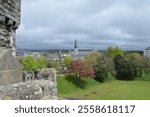 View from Cardiff Castle Keep overlooking the vibrant cityscape, lush greenery, and historical buildings, including the clock tower of Cardiff City Hall under a cloudy sky