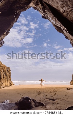 View from cave framing sandy beach and ocean with blue sky, natural frame composition
