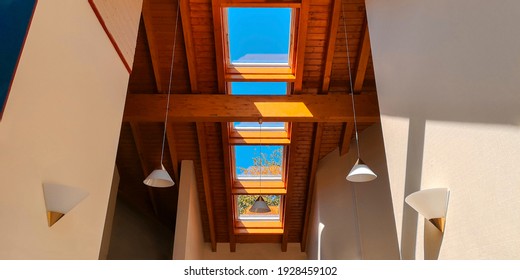 View Of Ceiling Of Gable Roof Without Attic With Three Plastic Windows, Finished With Clapboard,wooden Beam,identical Suspended White Frosted Lamps,2 Symmetrically On White Walls.Selective Focus.