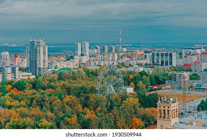 View Of The Central Park Of Perm From A Height. Ferris Wheel Among Green Trees. City Skyline.