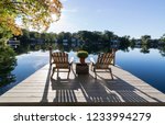View of chairs and dock on a pristine lake with reflections and shadows