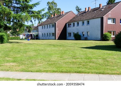 View Of Cheap Apartment With Green Lawn In Backyard In Sunny Summer With Trees And Clear Blue Sky Background. No People. 