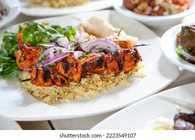 A view of a chicken kabob plate over rice.