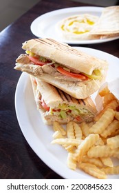 A View Of A Chicken Panini Sandwich, With Crinkle Cut French Fries.