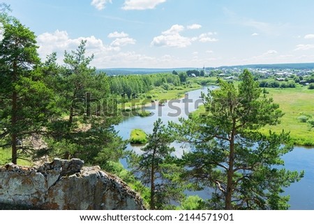 View of the Chusovaya river through trees and rocks on a sunny summer day, Ural, Sverdlovsk region, Russia.