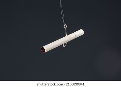 A View Of Cigarette Hanging From Metal Hook Isolated In Black Background