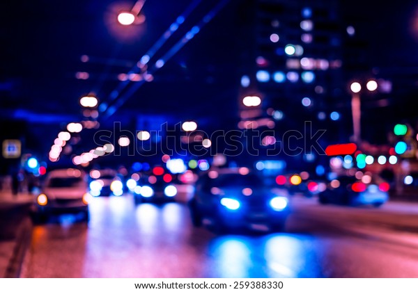 View of the city at night after the rain,\
the car driving on the road. In blue\
tones