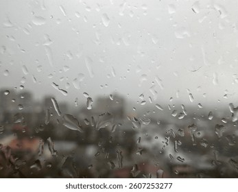 View of the city through the window on a rainy day with dark clouds water drops in blurred macro