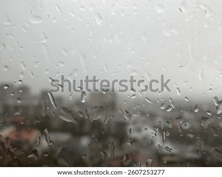 View of the city through the window on a rainy day with dark clouds water drops in blurred macro