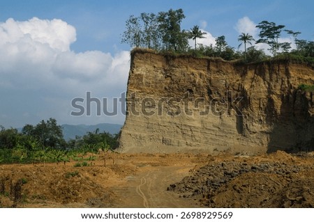 view of cliff edge with rock layer of sediment with blue sky and cloud