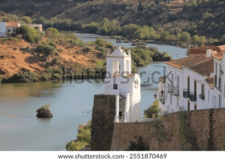 The view of Clock tower (Torre do Relogio) built in one of the towers of the town walls on the right bank of Guadiana. The background shows the lanscape and the river flowing through Mertola. Portugal