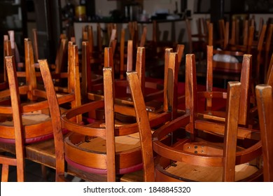 A View Of A Closed Restaurant Dining Room, Featuring All Of The Chairs Turned Over On The Tables. 