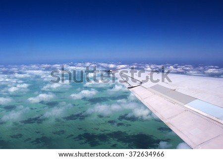 View of the cloud shadows over the Indian Ocean near Broome, North Western Australia   with the wing of the plane   in view  on a cloudy afternoon in summer Wet Season is beautifully exhilarating.