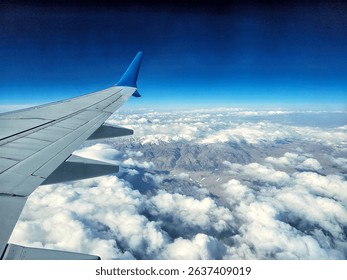 View of clouds and mountains from airplane window, bird's eye view, air travel.