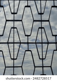 View of the cloudy sky behind the window grille 