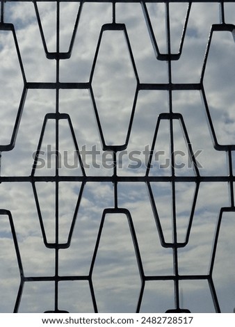 View of the cloudy sky behind the window grille 