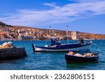 View of a coastal town and blue fishing boats in September 2023. Mytilene, Greece.
