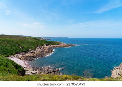 View of the coastline lined with pink sandstone cliffs and the deep blue waters of the Channel in Brittany - Shutterstock ID 2170598493