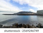 View of the coastline with rocky breakwaters, Kursaal building, and cityscape in San Sebastian, Spain. High quality photo