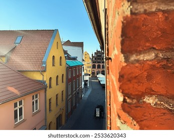 A view of colorful buildings with narrow street from behind a brick wall on a sunny day in the old city Stralsund, Germany - Powered by Shutterstock