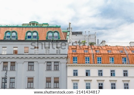 The view of colorful European houses with red roofs in sunny day. There are color Vienna building apartment with cloudy sky on background.
