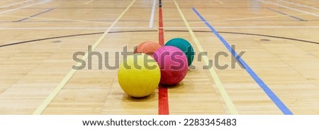 view of colorful rubber balls on the wooden floor of a gymnasium