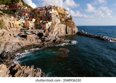 View of the colorful town of Manarola in Cinque Terre, Italy on a sunny summer day. Some clouds in the sky. 