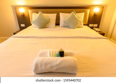View of comfortable bed with warm lighting in hotel bedroom decoration in cozy style (Focus at complimentary objects). Conceptual of a room in a home where people sleep.