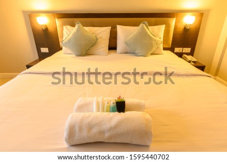 View of comfortable bed with warm lighting in hotel bedroom decoration in cozy style (Focus at complimentary objects). Conceptual of a room in a home where people sleep.