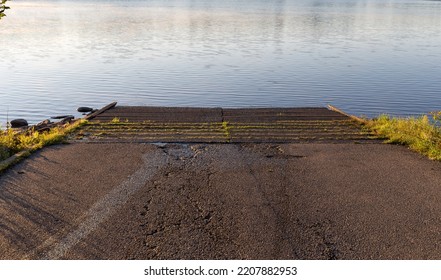 View Of A Concrete Boat Ramp Leading Into A Lake.