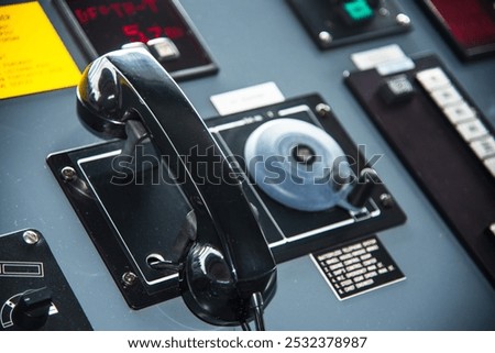 View of the control console on the navigational bridge of the cargo ship. Batteryless telephone on the first plan. 