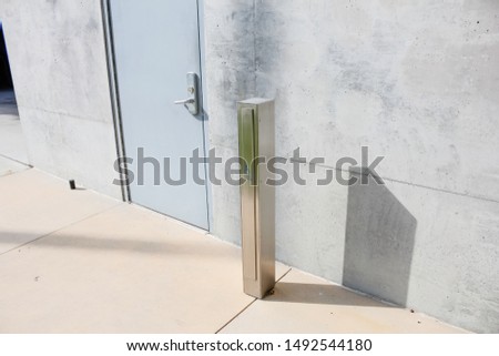 A view of a convenient handicap accessibility button post for opening a door, on the exterior of a building.