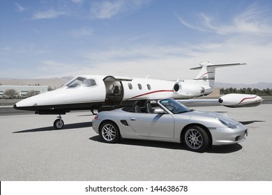 View of a convertible and private jet on landing strip in airport