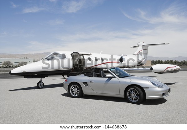 View of a convertible and private jet on landing\
strip in airport