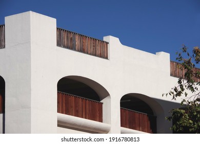 View of a corner of a downtown public parking structure in Spanish mission revival style with blue sky above in Southern California