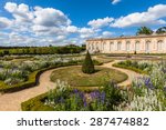 View of a corner of the garden in the Grand Trianon Palace on a sunny day with clouds and blue sky. A famous palace in the northwestern part of the Domain of Versailles, Paris, France