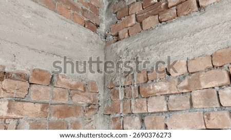 View of the corner where two brick walls meet with plaster and exposed brickwork in a construction setting