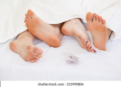 View Of Couple Using Contraception In Bed