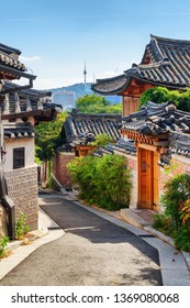 View Of Cozy Old Narrow Street And Traditional Korean Houses Of Bukchon Hanok Village In Seoul, South Korea. Seoul Tower On Namsan Mountain Is Visible On Blue Sky Background. Scenic Cityscape.