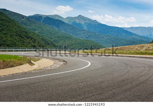 A view of a curved\
road. Driving a car on mountain road. Asphalt road in mountain.\
Empty road background