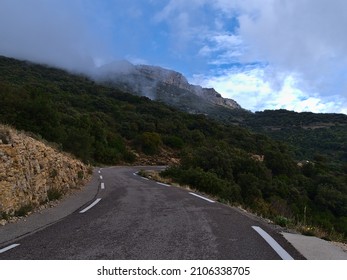 View of curvy mountain road D2 in Massif de la Sainte-Baume in Provence, France on cloudy day in autumn surrounded by forest in Natural Regional Park Sainte-Baume with rocky mountains. - Shutterstock ID 2106338705