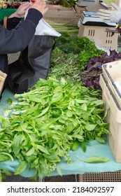 A View Of A Customer Preparing A Reusable Grocery Tote Bag Over A Farmers Market Vendor Table.