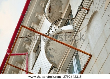 Сlose view of damaged balcony underside with crumbling concrete and visible steel reinforcement on aging apartment building, engineering inspection and repair concept. Hazardous residential balcony