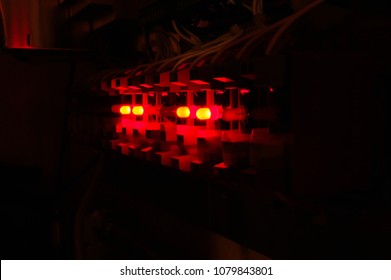 View in the dark of a row of solid state relays with red LED lights used for data acquisition and control systems.