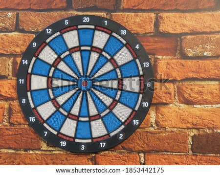 A view of a dartboard on an old brown brick wall