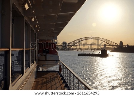 A view from the deck of a ship looking out towards the Sydney Harbour Bridge at what appears to be sunrise or sunset.